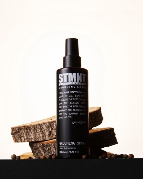 STMNT Grooming Spray fles met hout en koffiebonen op achtergrond.