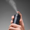 Handen die een hairspray sprayen voor een volumineuze haarstijl.