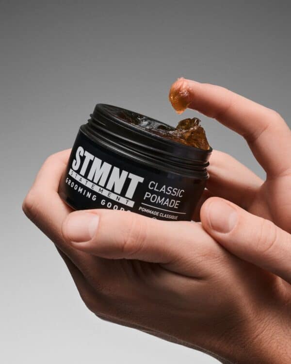 Finesse Beauty Classic Pomade in zwart potje met hand die product aanraakt.