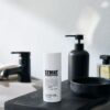 STMNT aftershave lotion op zwart houten plank in badkamer.